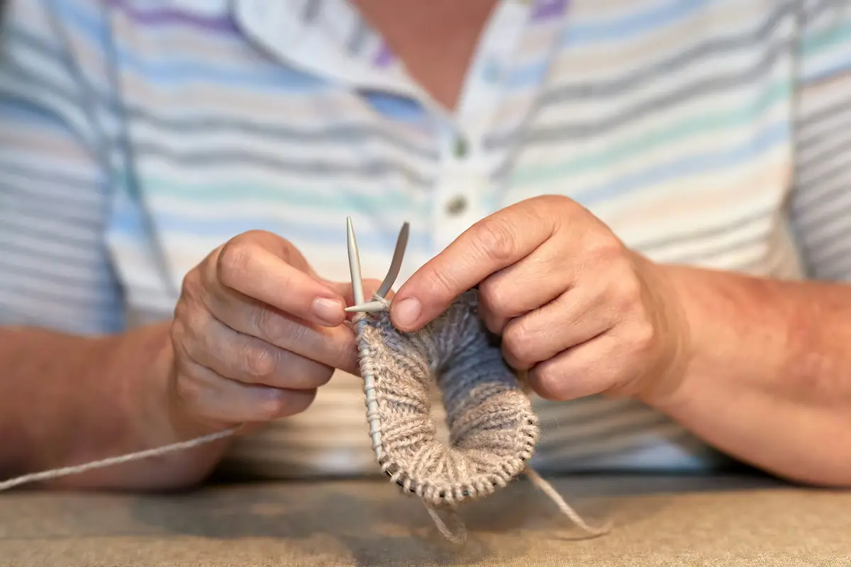 Hands knitting a sock on double-pointed needles
